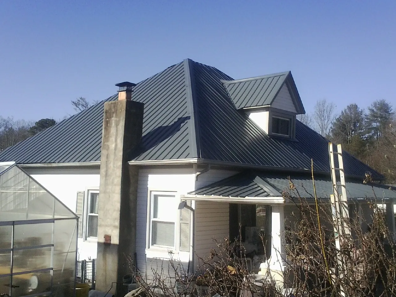 Dark blue standing seam metal roof on a white farmhouse with dormer — Slate & Tile Roof Repair by Roofing Brothers in Scotts Valley