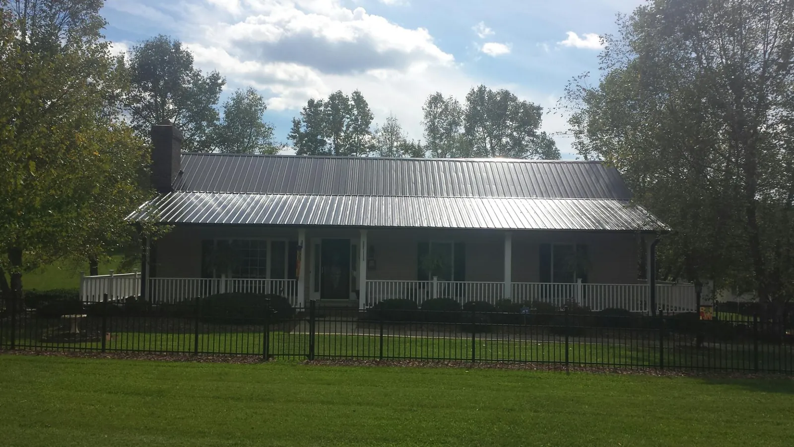 Gray metal roof on a brick ranch with a full width front porch — Gutter Guard Installation work by our crew in Scotts Valley