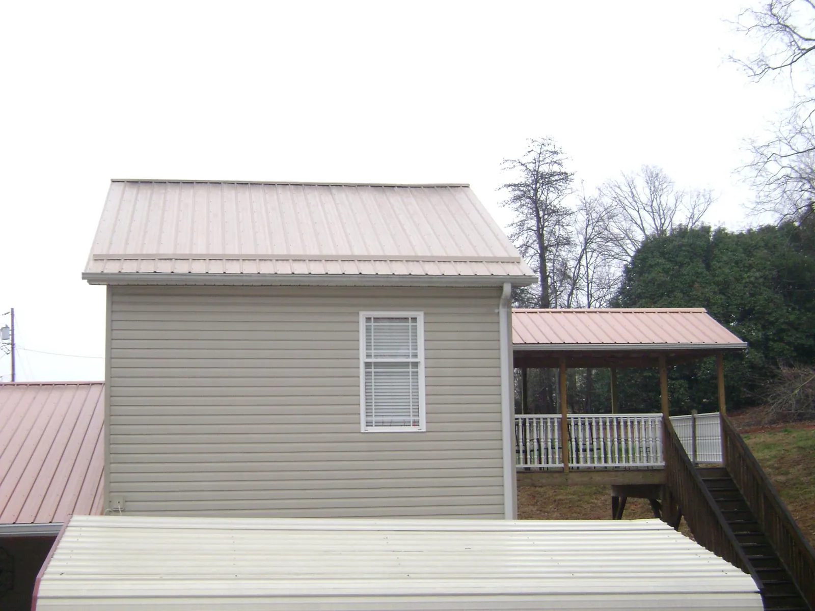Tan metal roofs on a two story addition and attached porch, from a Roof Replacement job in Scotts Valley