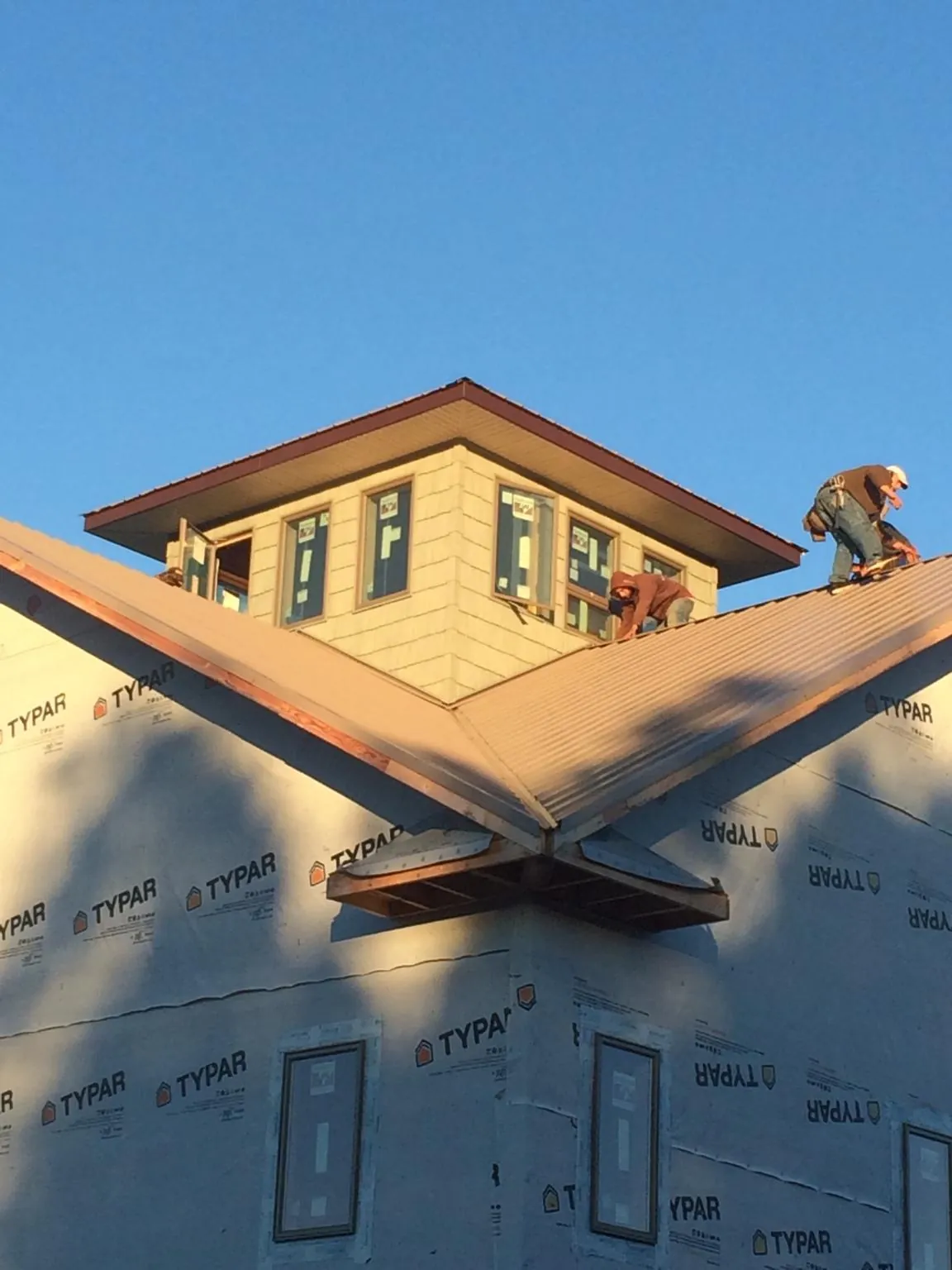 Roofers working around a rooftop cupola on a new metal roof at sunset — Roof Waterproofing in Scotts Valley by Roofing Brothers